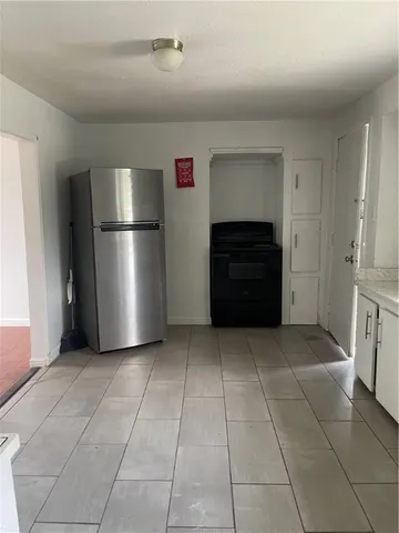 a view of a refrigerator in kitchen and an empty room