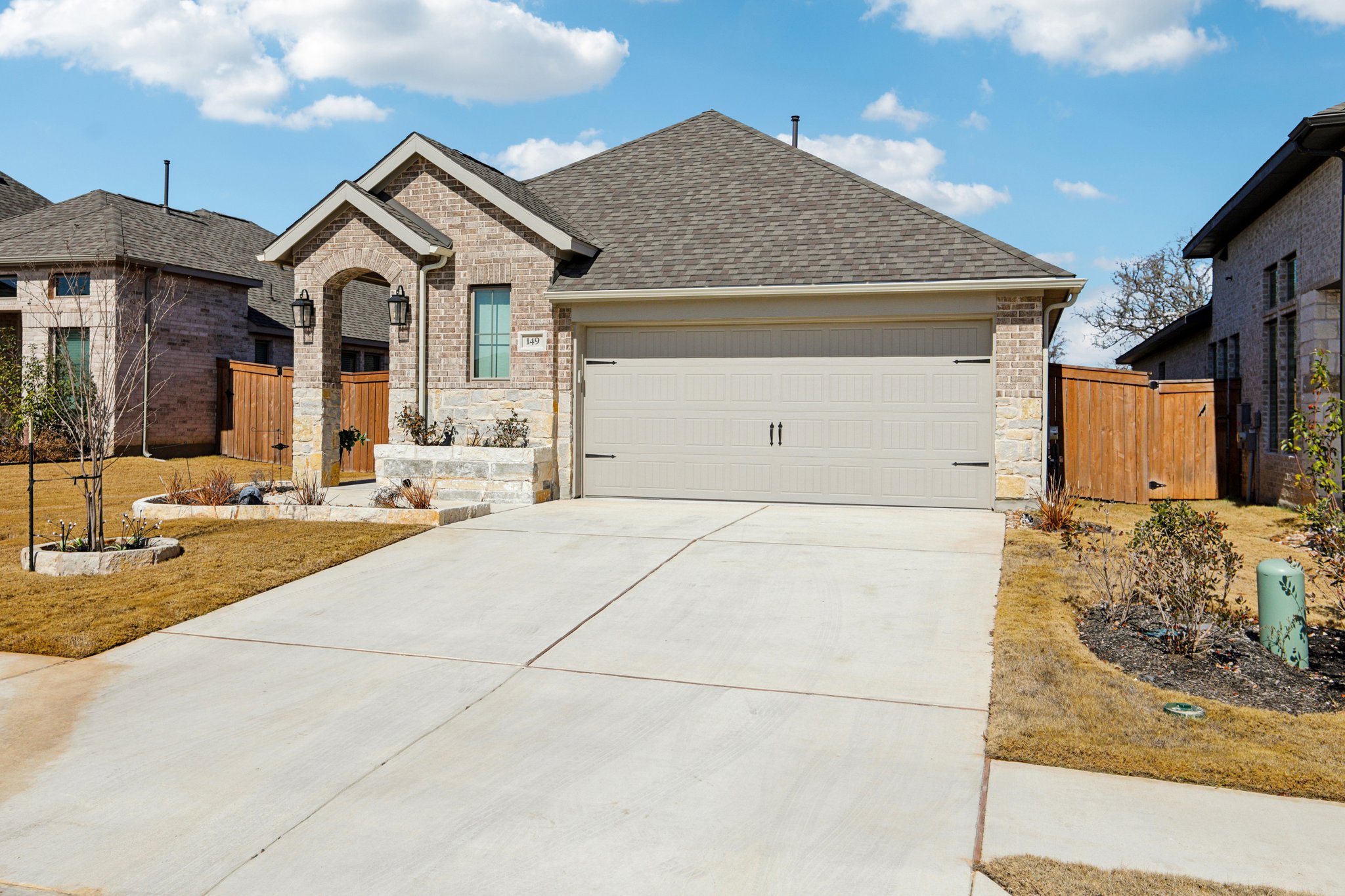 French country style house with stone siding, a gate, driveway, and a garage