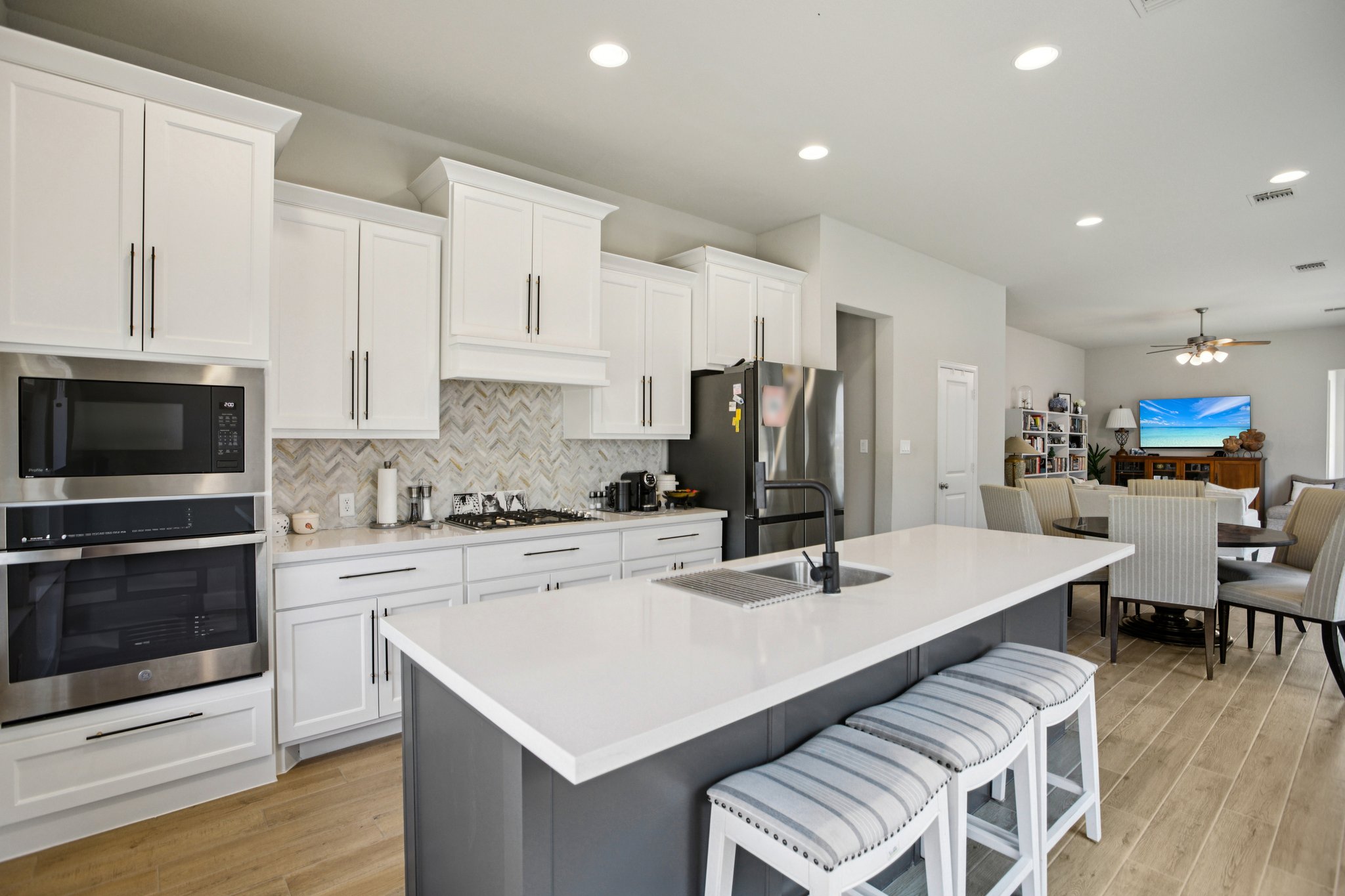 149 Plumbago Loop Bastrop, TX 78602 - Photo 15 of 33 Two tone kitchen featuring stainless steel appliances, a kitchen breakfast bar, a center island with sink, dual tone cabinets, and a ceiling fan