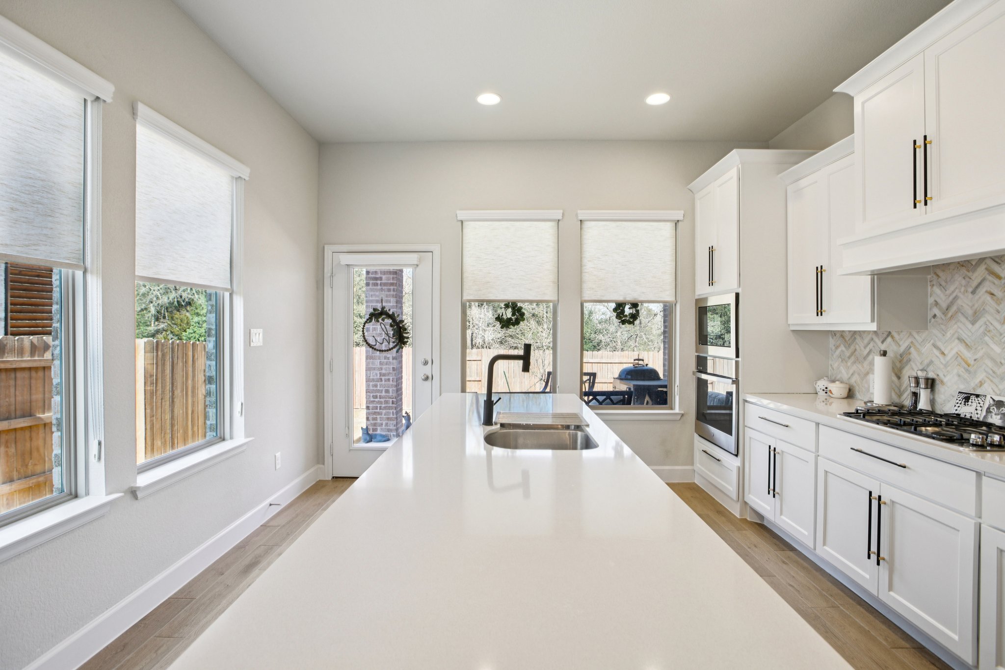 149 Plumbago Loop Bastrop, TX 78602 - Photo 16 of 33 Kitchen with white cabinets, light wood-style floors, backsplash, stainless steel appliances, and recessed lighting