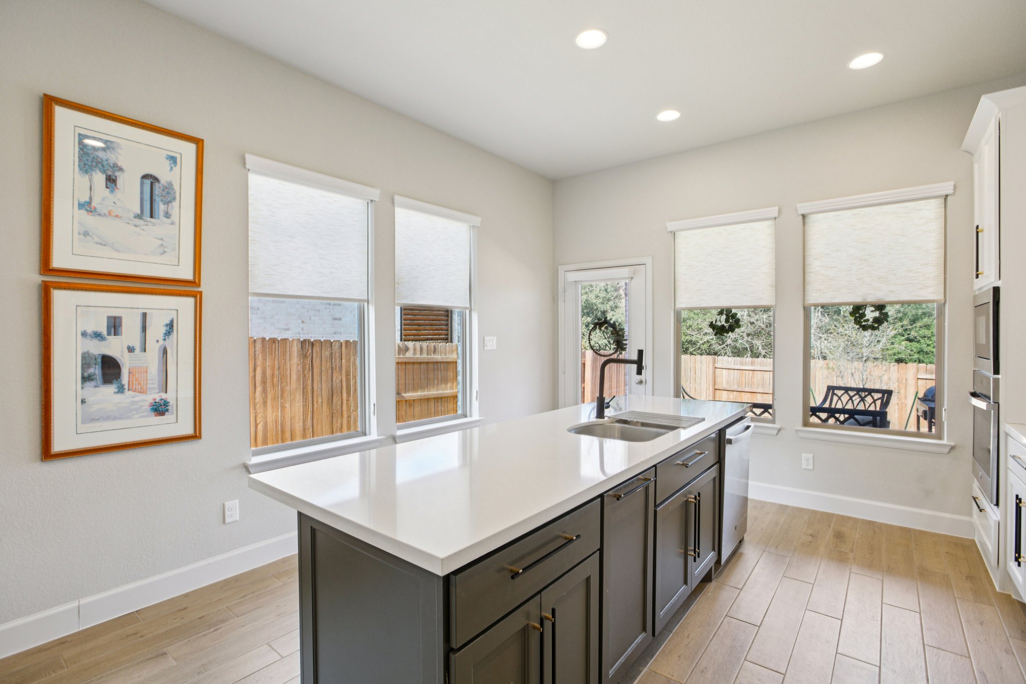 149 Plumbago Loop Bastrop, TX 78602 - Photo 17 of 33 Two tone kitchen with light wood-type flooring, an island with sink, recessed lighting, healthy amount of natural light, and dual tone cabinets