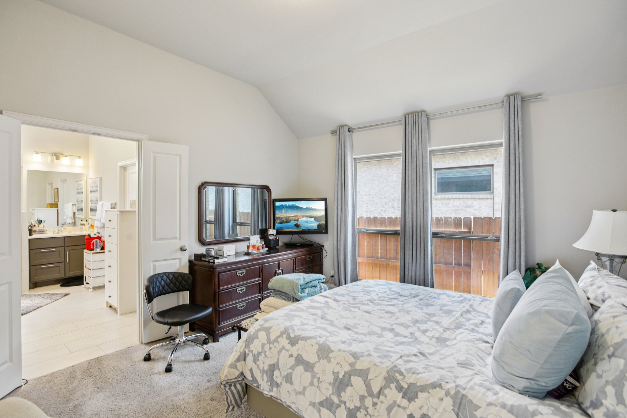 149 Plumbago Loop Bastrop, TX 78602 - Photo 25 of 33 Bedroom featuring lofted ceiling, light carpet, light tile patterned flooring, and ensuite bathroom