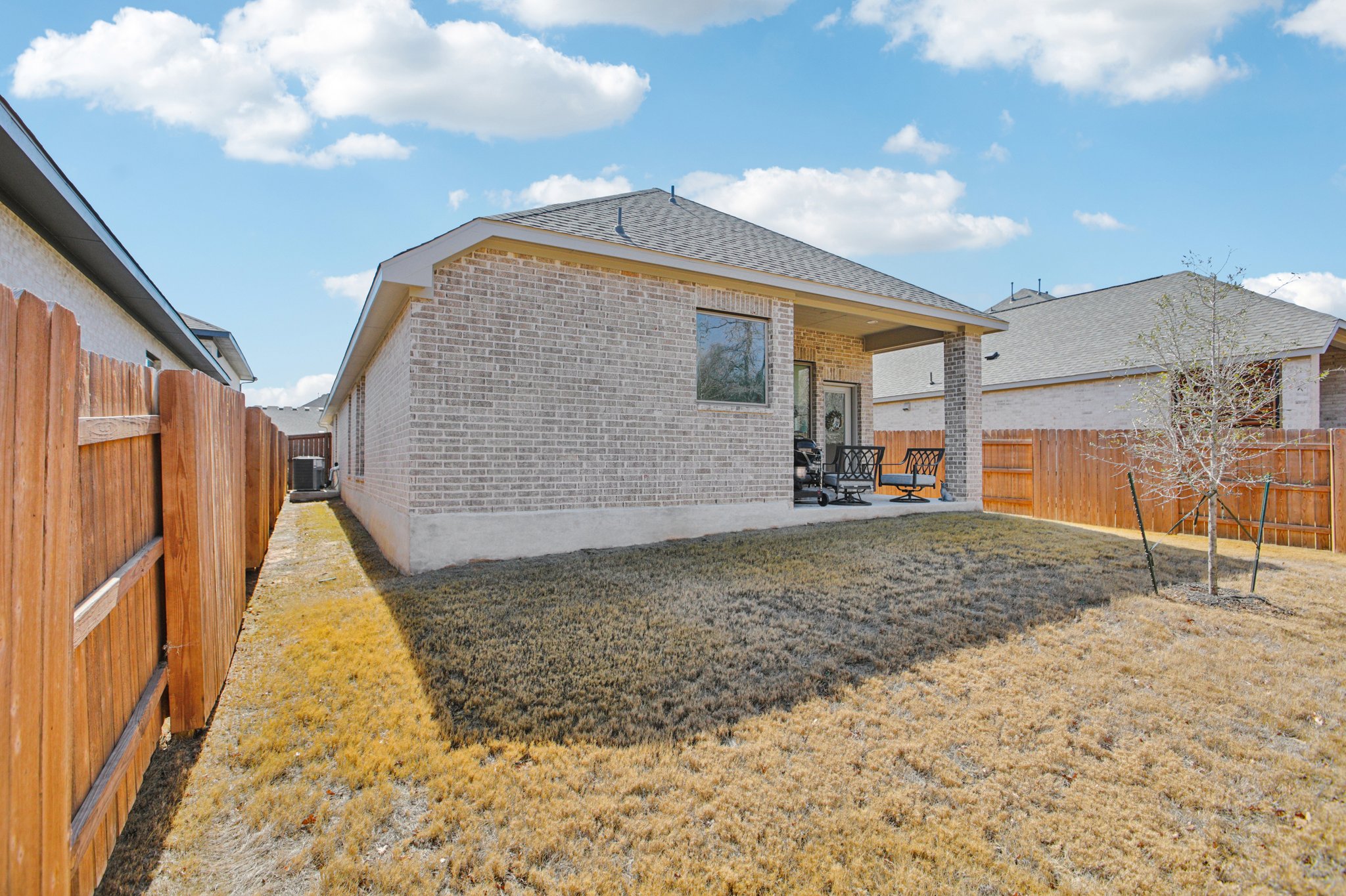 149 Plumbago Loop Bastrop, TX 78602 - Photo 30 of 33 Rear view of house with brick siding, a patio area, and a fenced backyard