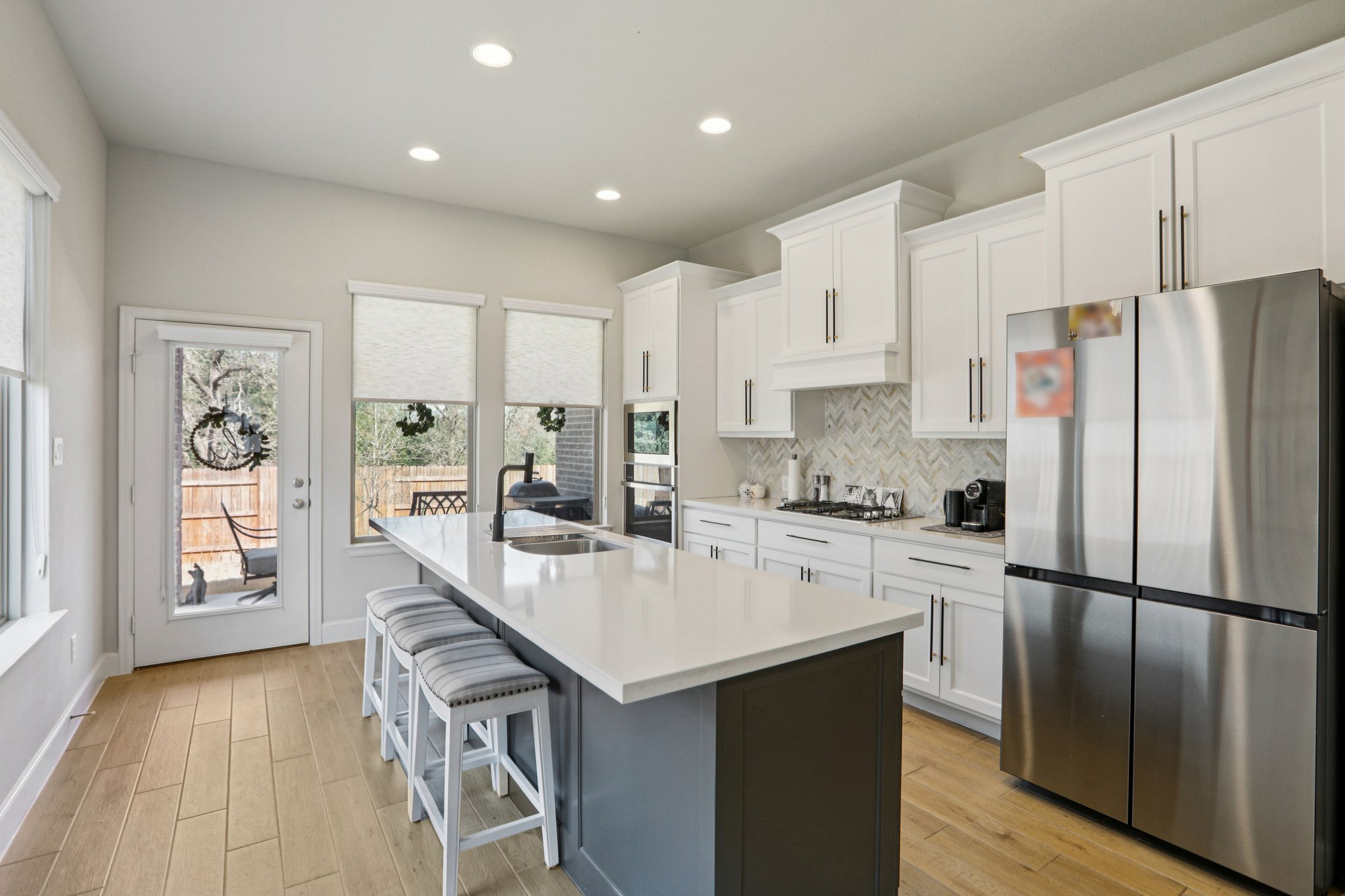 149 Plumbago Loop Bastrop, TX 78602 - Photo 3 of 33 Kitchen featuring stainless steel appliances, light wood-style flooring, a breakfast bar area, a center island with sink, and recessed lighting
