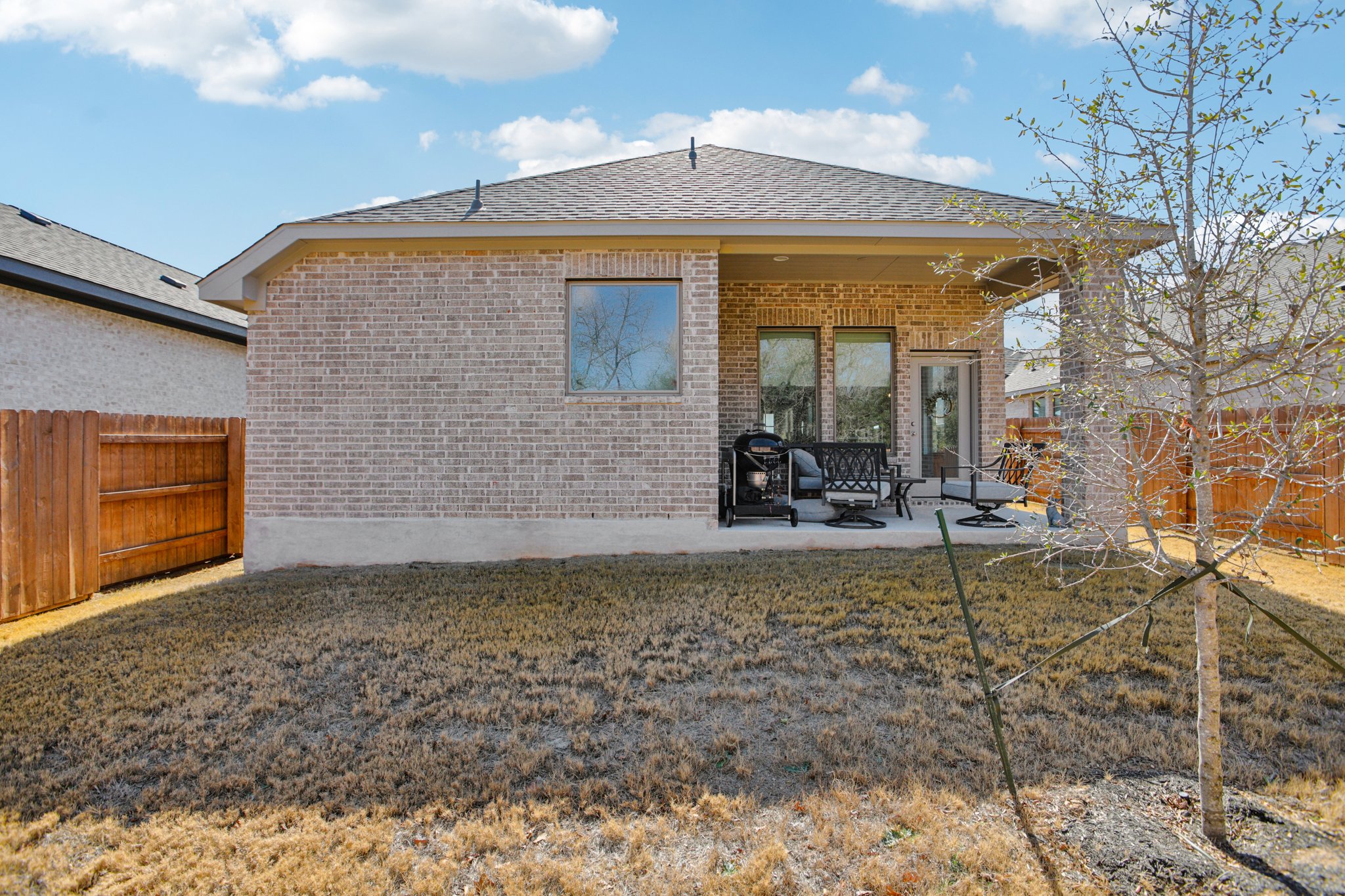 149 Plumbago Loop Bastrop, TX 78602 - Photo 31 of 33 Back of house featuring a fenced backyard, a shingled roof, a patio, and brick siding