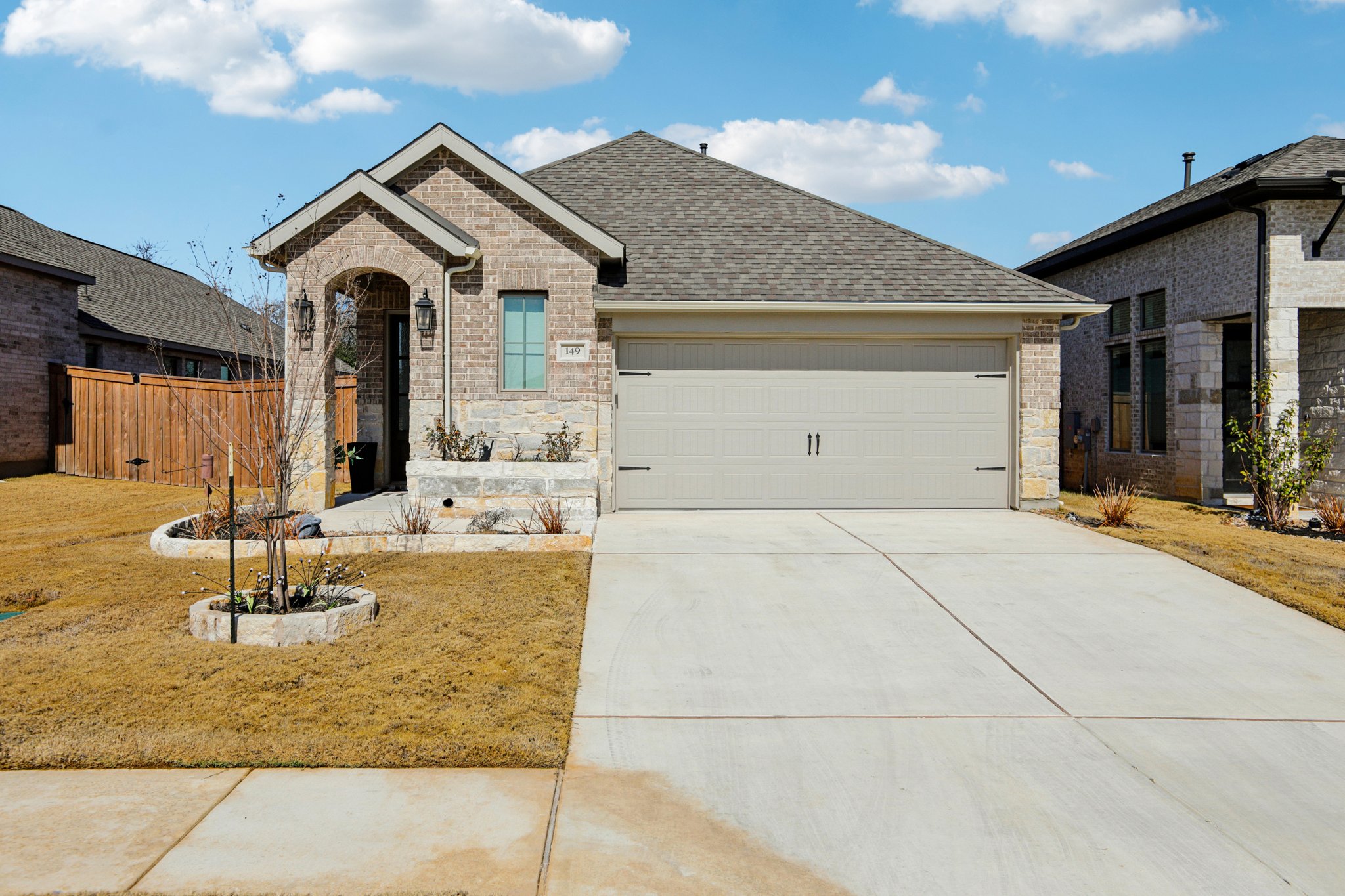 149 Plumbago Loop Bastrop, TX 78602 - Photo 5 of 33 View of front facade featuring stone siding, driveway, a shingled roof, and a garage