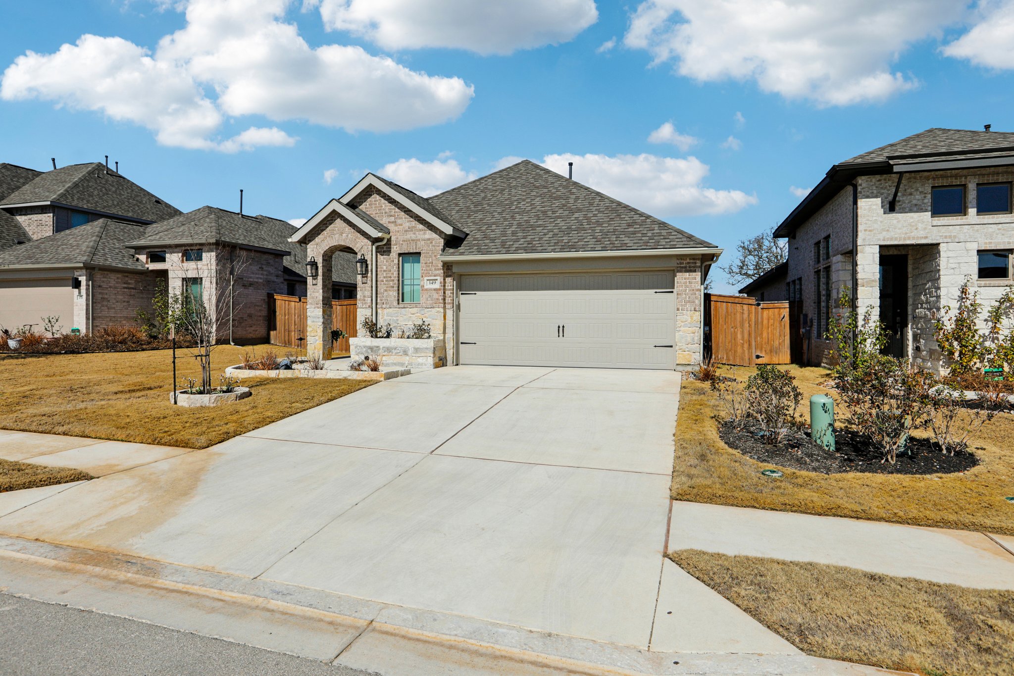 149 Plumbago Loop Bastrop, TX 78602 - Photo 8 of 33 French country home with driveway, an attached garage, brick siding, stone siding, and a shingled roof