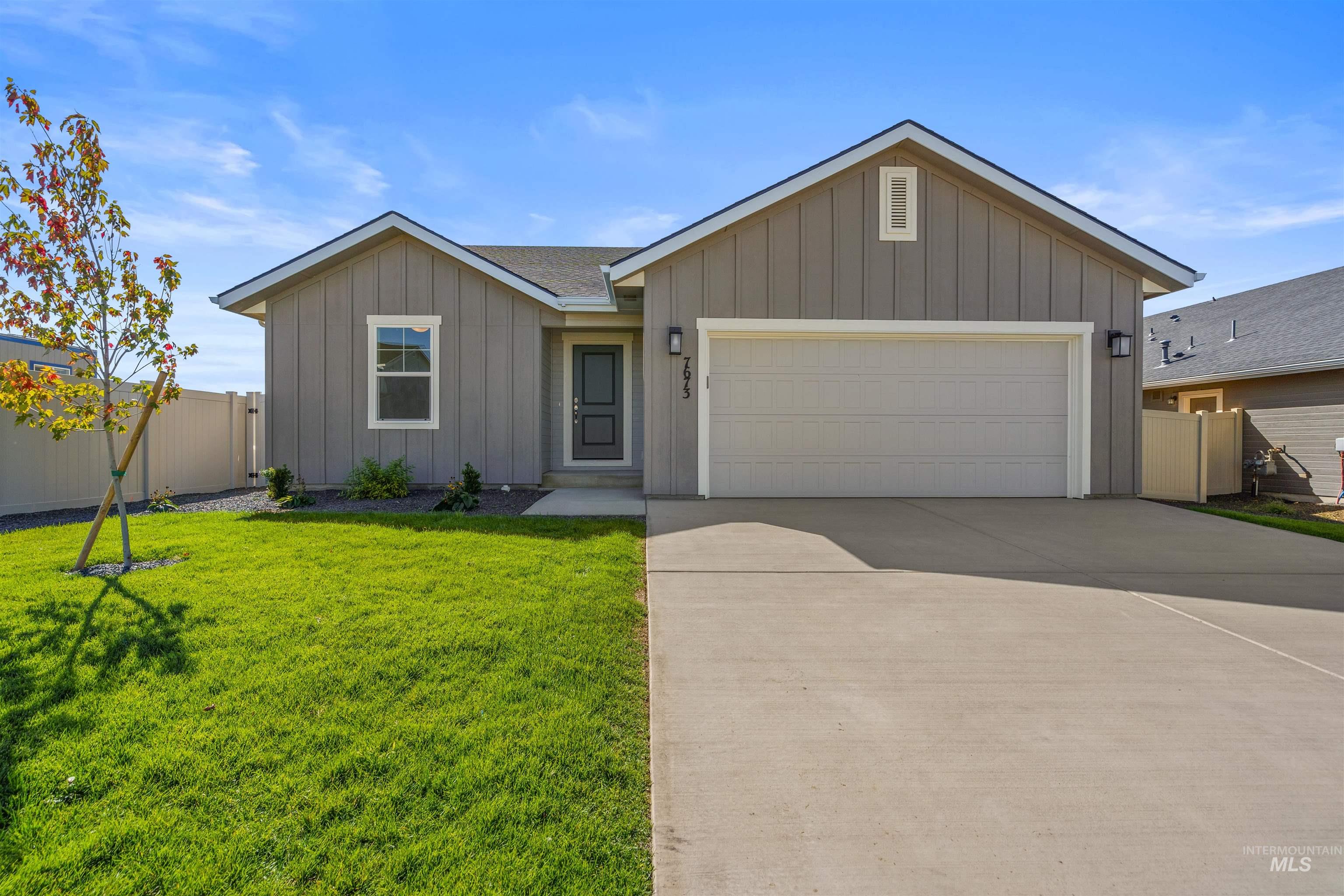 View of front of house featuring stone siding, a garage, board and batten siding, and driveway