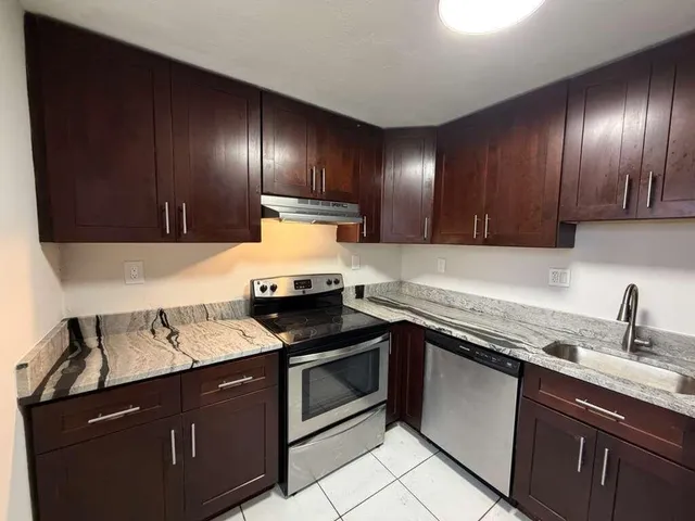 a kitchen with granite countertop wood cabinets stainless steel appliances and a sink