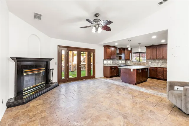 a view of a kitchen with a stove cabinets a ceiling fan and a fireplace