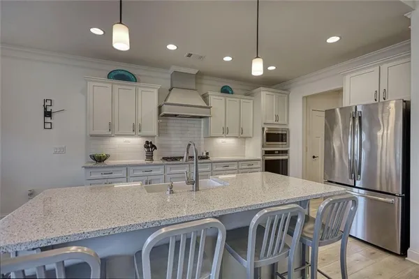 a kitchen with kitchen island a refrigerator a sink and a stove