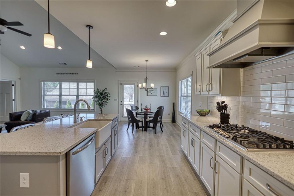 612 Haven Way Monroe, GA 30655 - Photo 15 of 44 a kitchen with stainless steel appliances a stove a sink a dining table and chairs with wooden floor