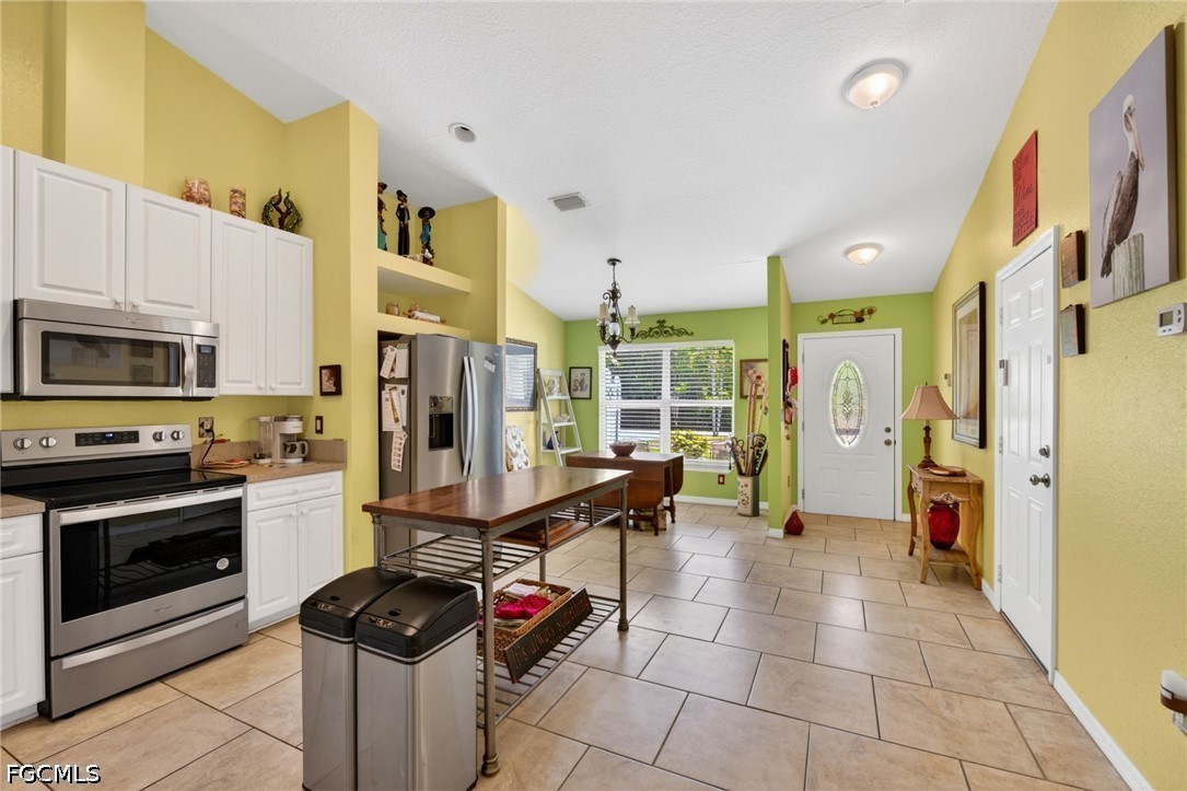 5520 Phillips Street Bokeelia, FL 33922 - Photo 14 of 50 a kitchen with stainless steel appliances kitchen island granite countertop a refrigerator and a stove top oven