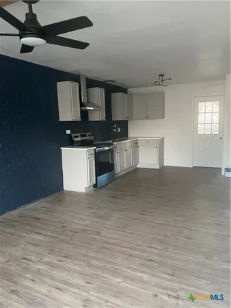 a large white kitchen with granite countertop a stove top oven a sink and dishwasher