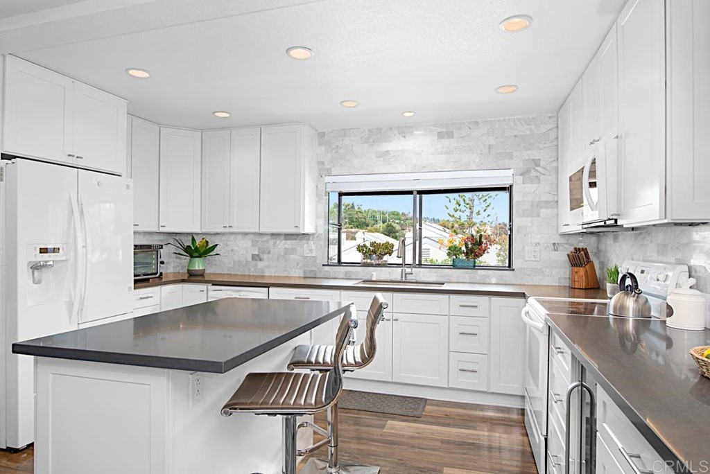 2372 Altisma Way, Unit C Carlsbad, CA 92009 - Photo 14 of 30 a kitchen with granite countertop a sink a center island cabinets and stainless steel appliances