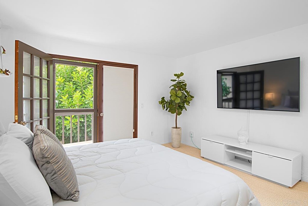 2372 Altisma Way, Unit C Carlsbad, CA 92009 - Photo 20 of 30 a bedroom with a large bed and a flat tv screen