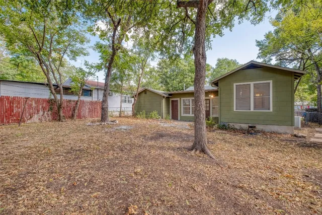 a view of a house with a yard and large tree