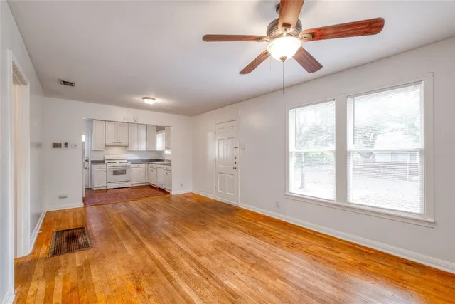 a large white kitchen with kitchen island a stove a sink cabinets and a window