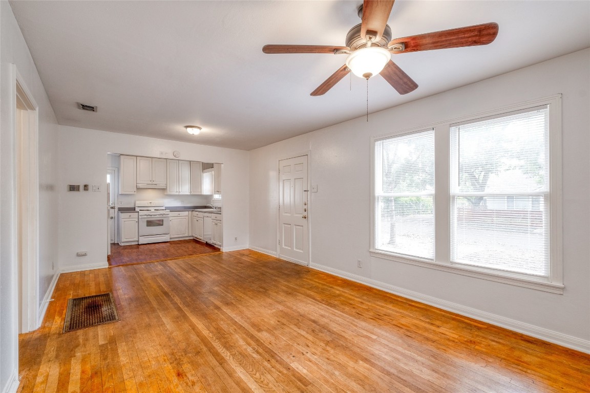 611 Genard Street Austin, TX 78751 - Photo 5 of 26 a large white kitchen with kitchen island a stove a sink cabinets and a window