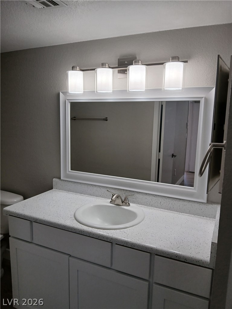 555 East Silverado Ranch Boulevard, Unit 1098 Las Vegas, NV 89183 - Photo 6 of 10 A pristine vanity with a large mirror and modern lighting fixtures anchors this well-appointed bathroom.