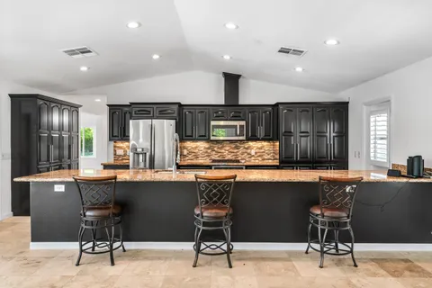 a kitchen with stainless steel appliances kitchen island granite countertop a table chairs in it and wooden floors