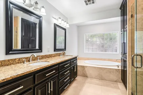a bathroom with a granite countertop bathtub sink vanity and mirror