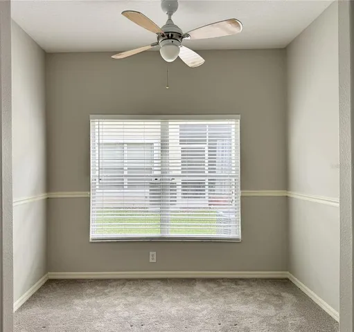 an empty room with a window and a ceiling fan