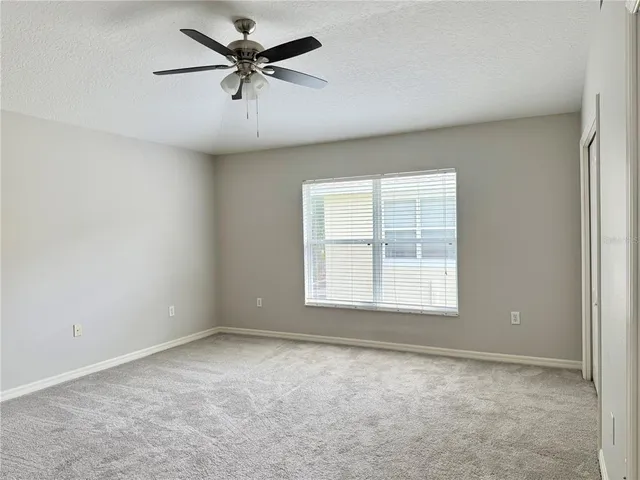 an empty room with a window and a fan