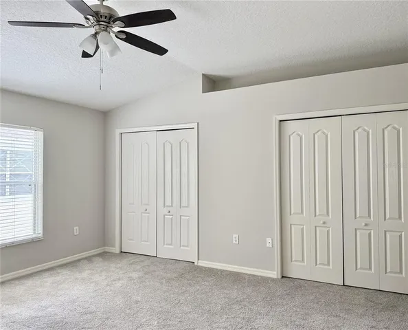 an empty room with windows and fan