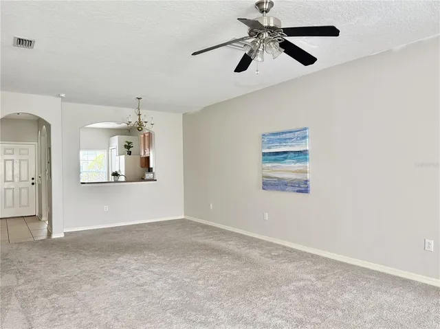 en empty room with chandelier fan and windows