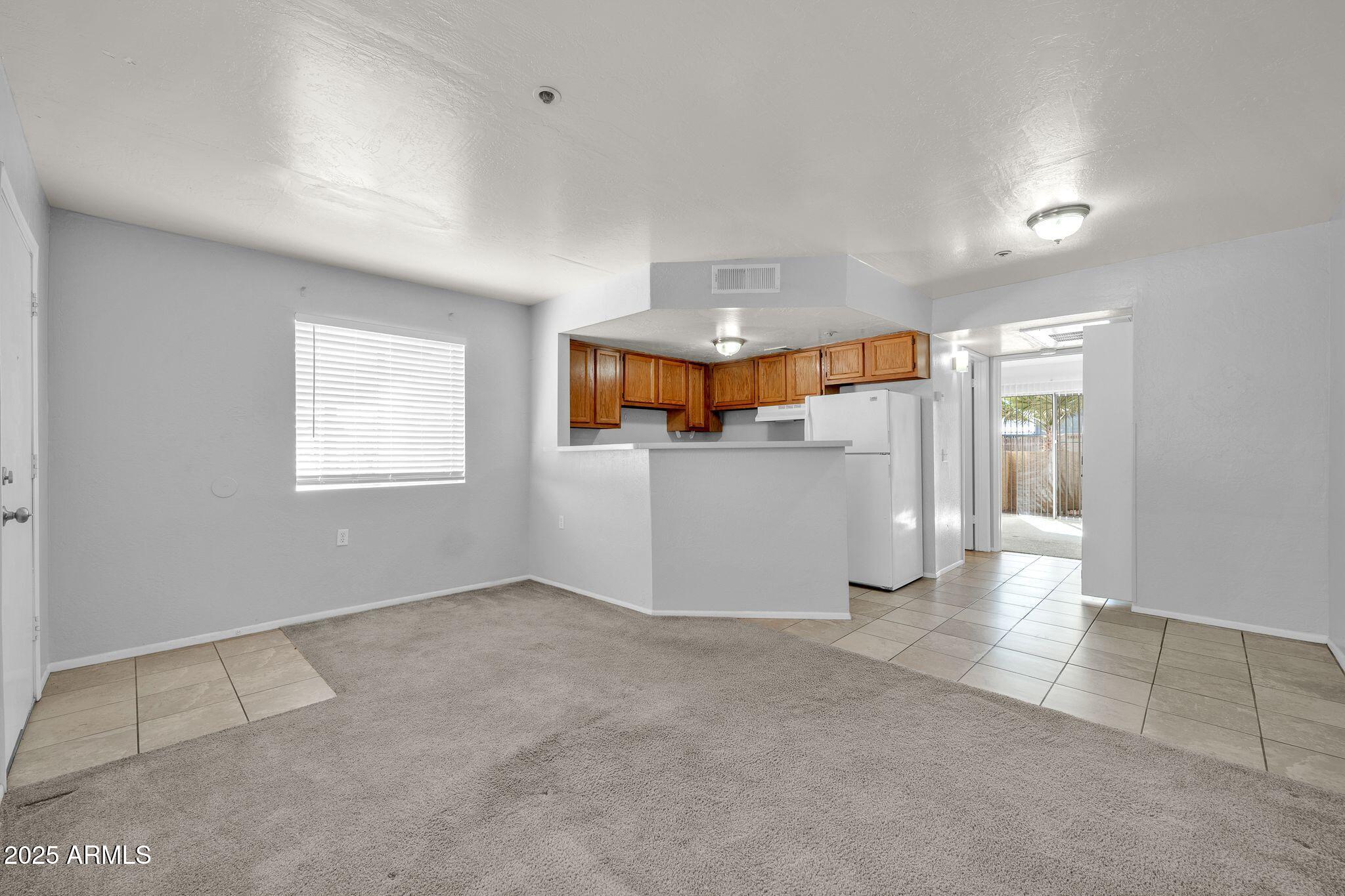 12221 West Bell Road, Unit 187 Surprise, AZ 85378 - Photo 2 of 11 an empty room with a kitchen view and a window