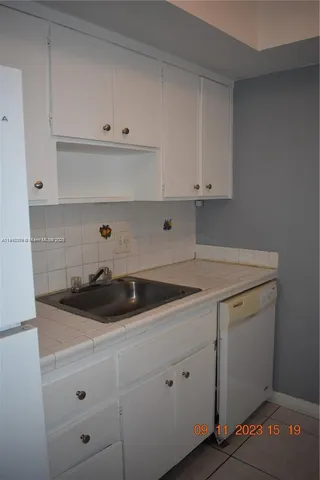 a kitchen with white cabinets and a stove with wooden floor