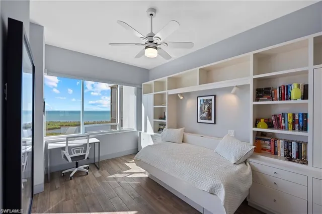 a bedroom with a bed and a large window with book shelf