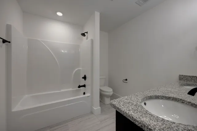 a bathroom with a granite countertop sink a toilet and bathtub
