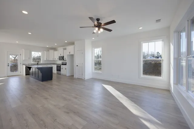 a view of a big room with wooden floor and a kitchen