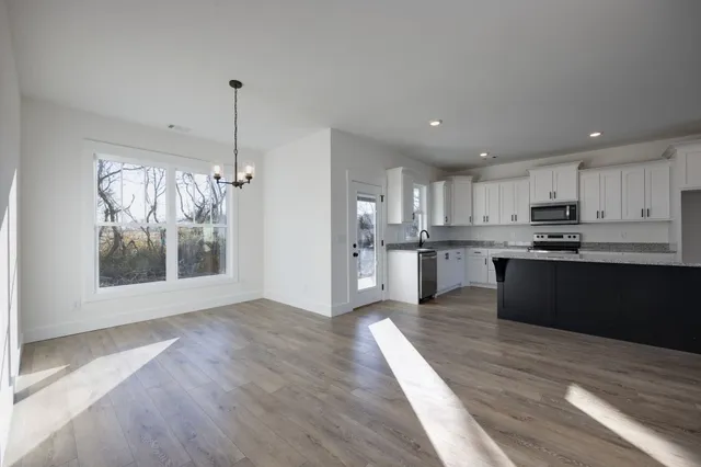 a view of kitchen with granite countertop stainless steel appliances refrigerator sink and cabinets