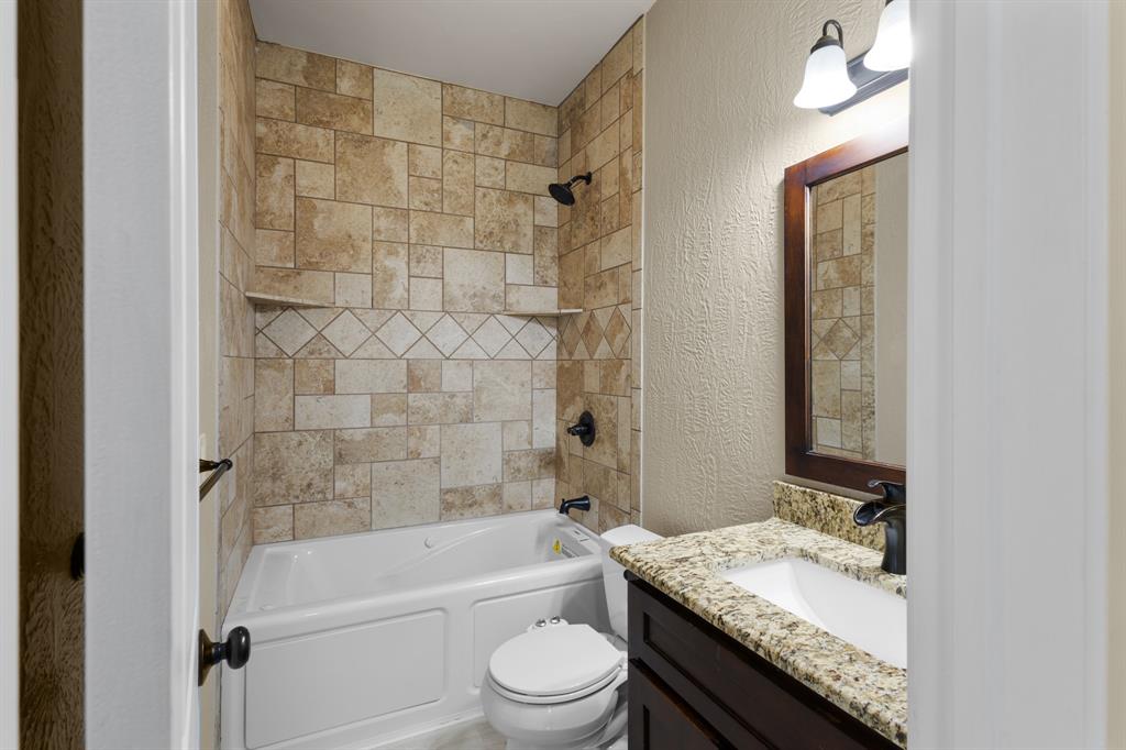 202 Blocker Bridgeport, TX 76426 - Photo 16 of 27 a bathroom with a granite countertop sink toilet a mirror and shower