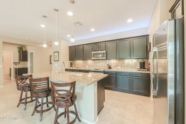a kitchen with kitchen island granite countertop wooden cabinets and refrigerator