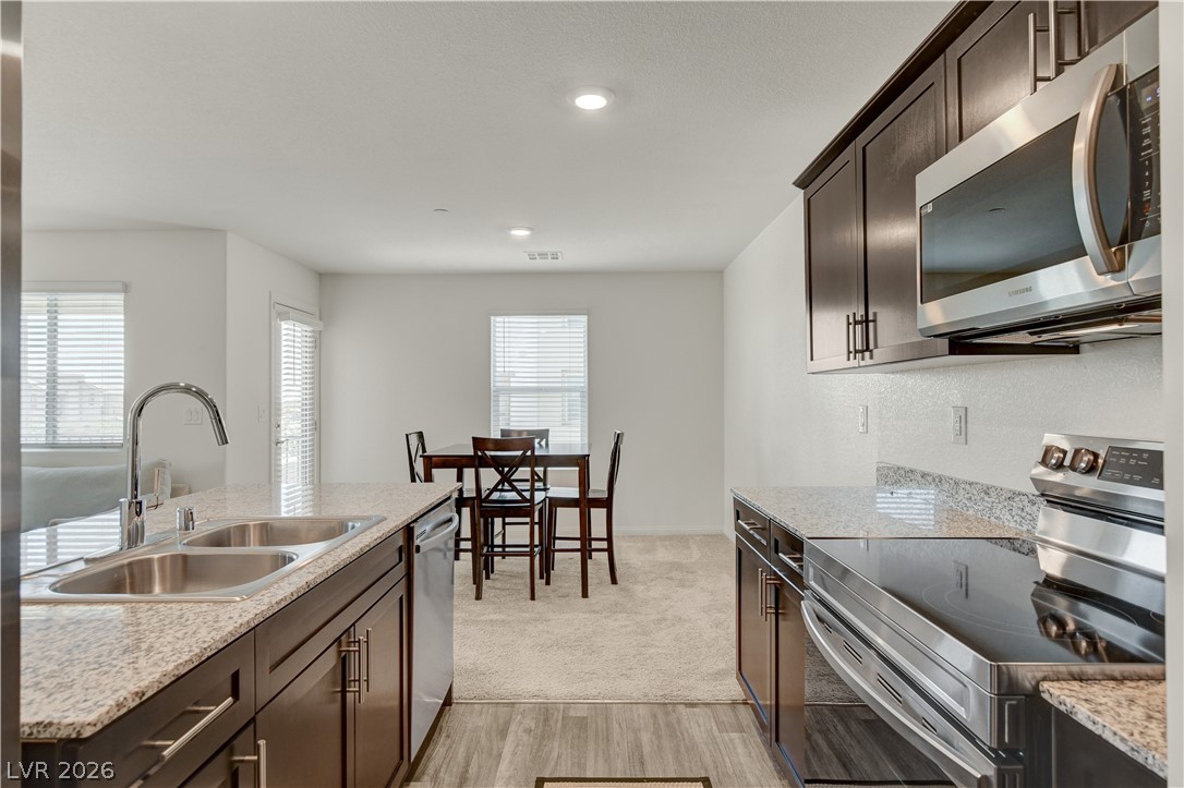 6924 Spicy Merlot Street North Las Vegas, NV 89086 - Photo 18 of 83 Modern kitchen with granite counters and stainless steel appliances seamlessly transitions to a dining area.