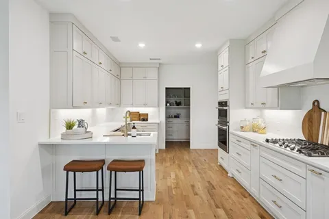 a kitchen with stainless steel appliances kitchen island granite countertop a table chairs stove and white cabinets