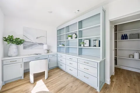 a kitchen with white cabinets and wooden floor