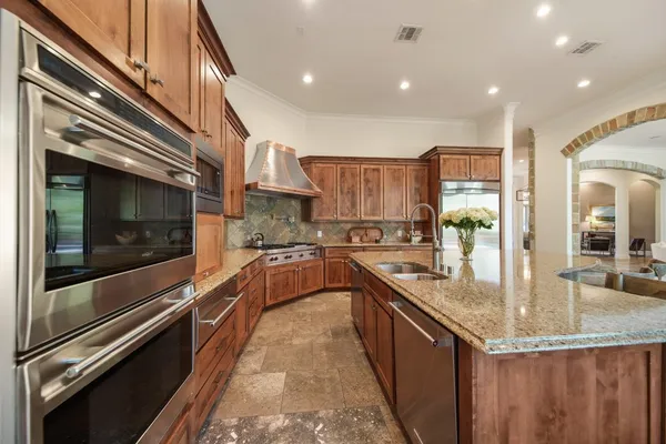 a kitchen with stainless steel appliances granite countertop a sink a stove and a wooden floors