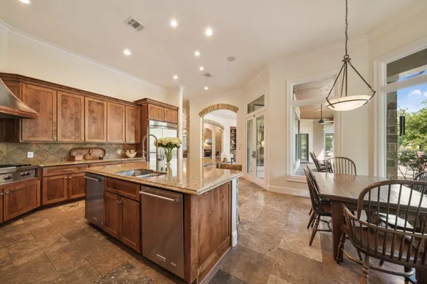 a kitchen with stainless steel appliances granite countertop a stove top oven a sink dishwasher a dining table and chairs with wooden floor