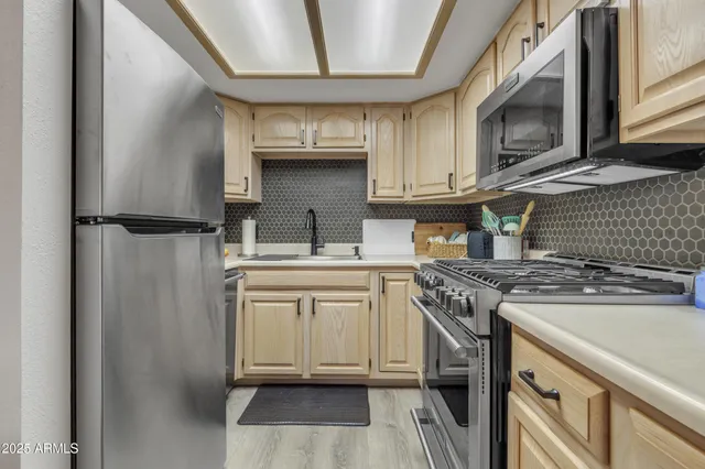 a kitchen with stainless steel appliances granite countertop a refrigerator a stove and a sink with cabinets