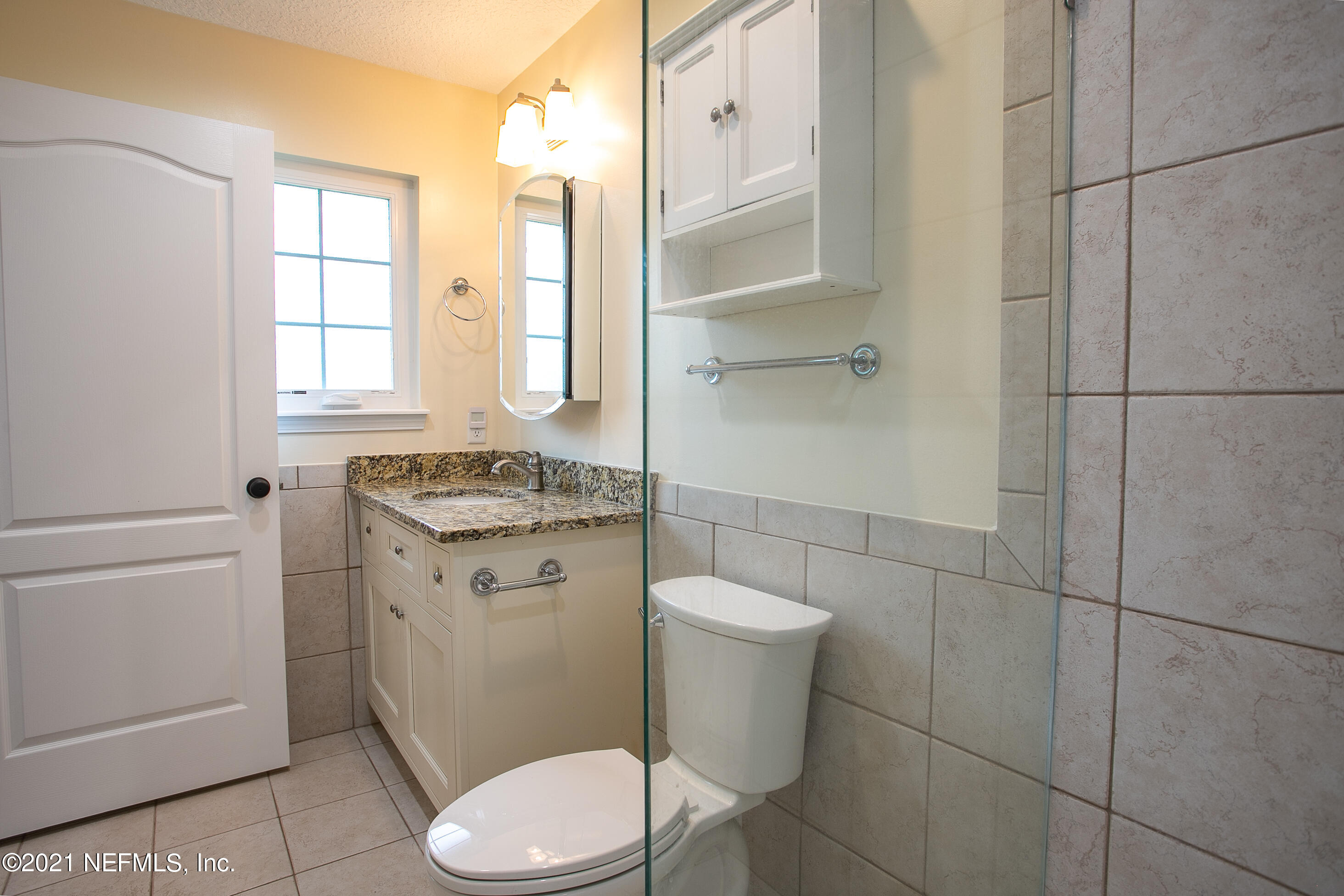 96165 Pirates Bluff Road Yulee, FL 32097 - Photo 16 of 28 a bathroom with a granite countertop toilet a sink a mirror and a shower