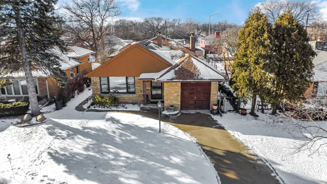 a front view of a house with a yard covered with snow and trees