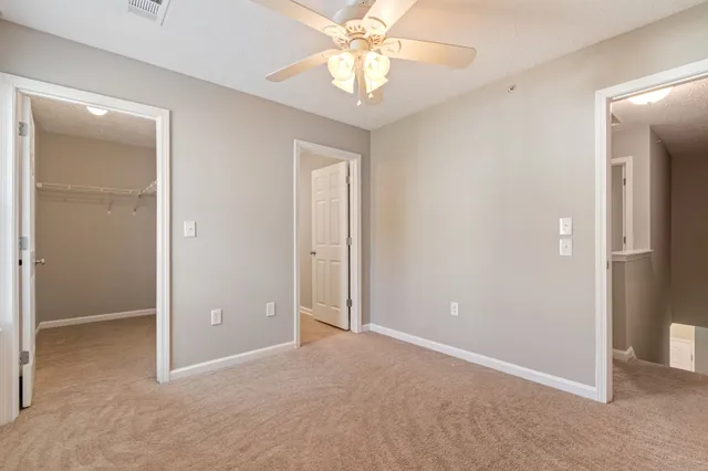 an empty room and chandelier fan in hallway