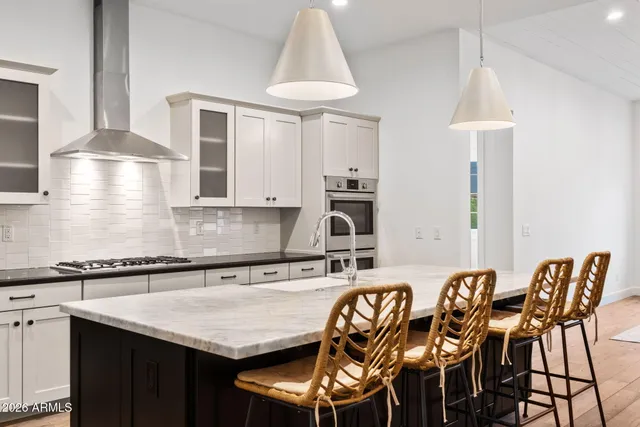 a kitchen with stainless steel appliances granite countertop a table chairs in it and wooden floors