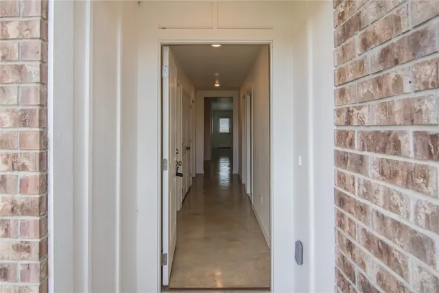 a view of a hallway with a door and a wooden floor