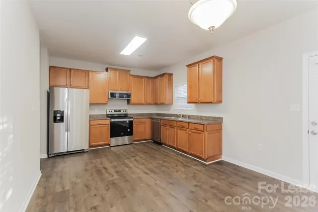 a kitchen with granite countertop a refrigerator and wooden cabinets
